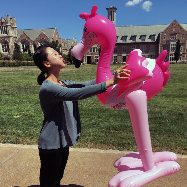 student holding and kissing inflatable flamingo