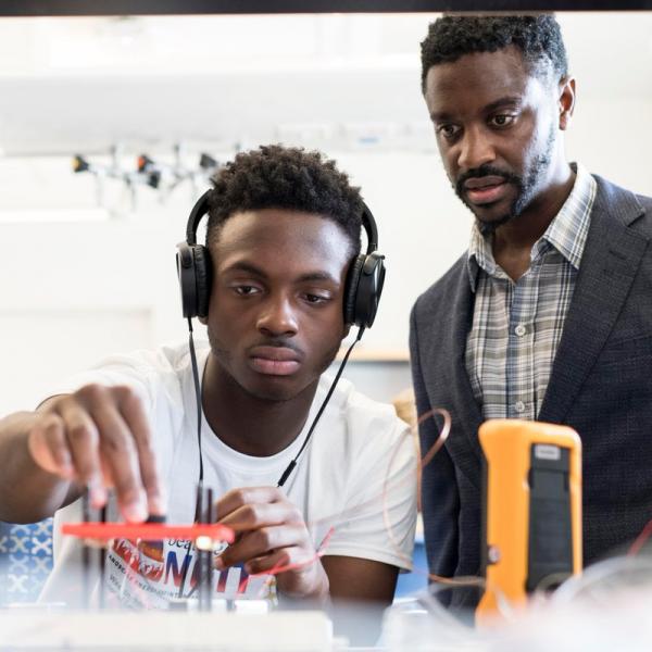 engineering student with headphones being observed by professor